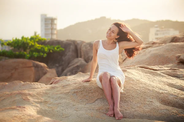 Mooie brunette meisje zit op steen — Stockfoto