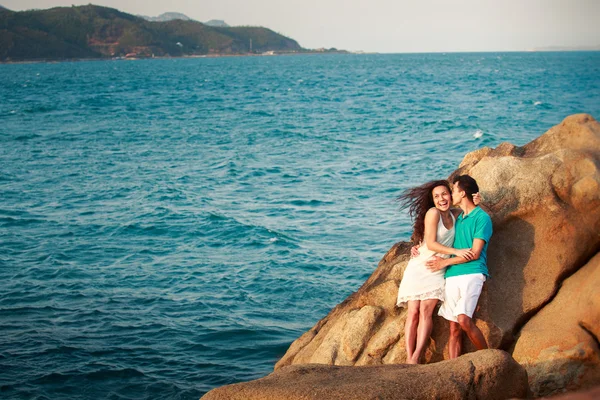 Menina e cara na pedra contra o mar — Fotografia de Stock