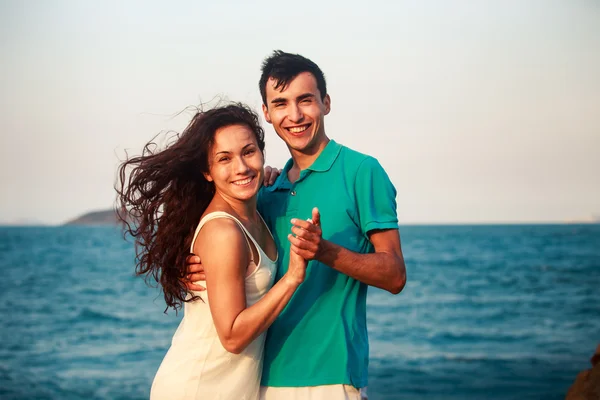 Chica y chico abrazándose contra el mar azul — Foto de Stock