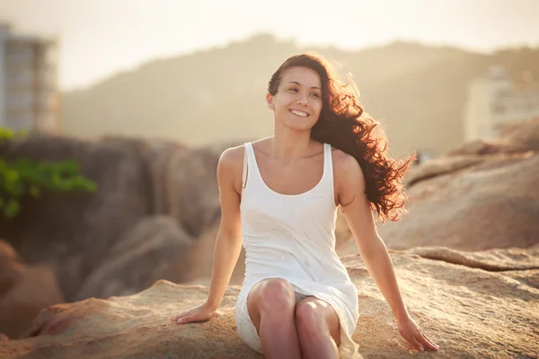 Söt brunett tjej sitter på sten — Stockfoto