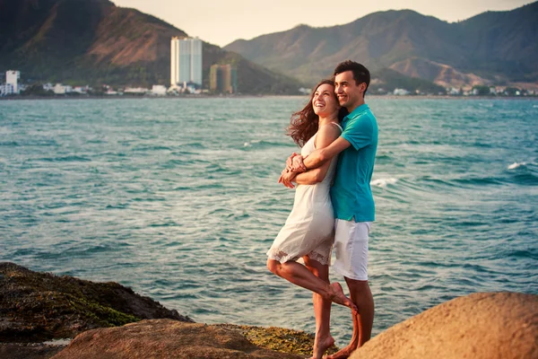 Chica y chico abrazándose contra el mar azul — Foto de Stock