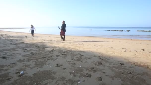 Gitarzysta z piękną dziewczyną chodzenie na plaży — Wideo stockowe