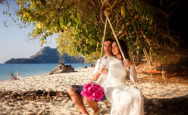 Bride with pink bouquet and groom on rope swing — Stock Photo, Image