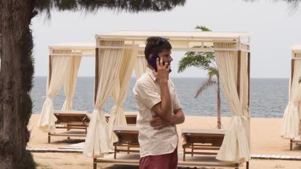 Tipo hablando teléfono en la playa — Vídeos de Stock