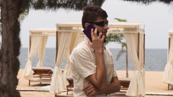 Facet mówi telefon na plaży — Wideo stockowe