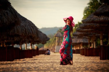 slim girl in red hat looks into sky among defocused umbrellas