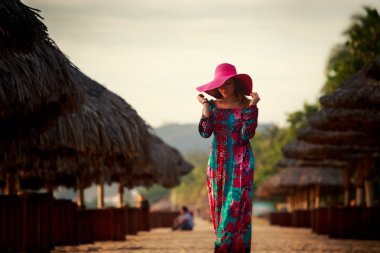 slim girl in red hat looks down among defocused umbrellas