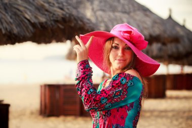 brunette girl in big red hat smiles at defocused umbrella