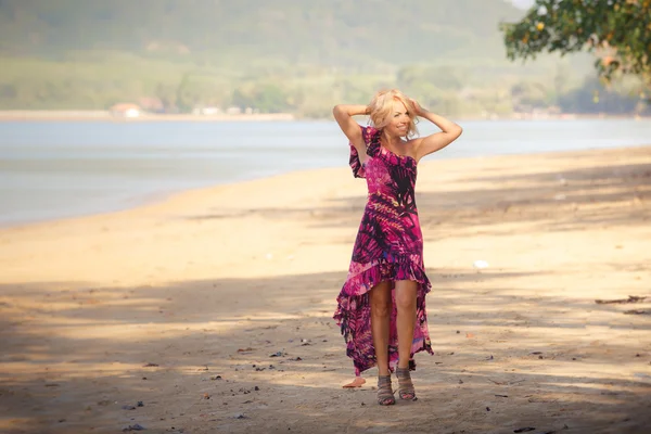 Blonde girl smoothes hair against sea — Stock Photo, Image