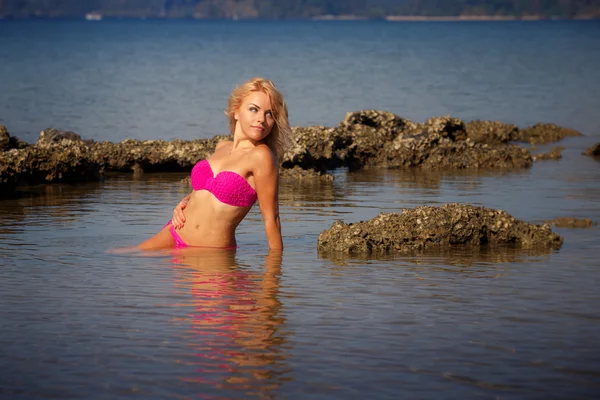 Blondes Mädchen im Badeanzug halb im Meerwasser — Stockfoto