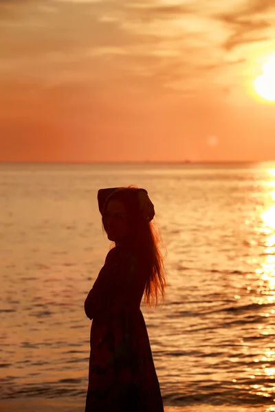 Szczupła dziewczyna w długiej sukni przed wschodem słońca nad morzem — Zdjęcie stockowe