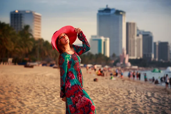 Mince fille dans long et grand chapeau sur la plage contre ville mer — Photo