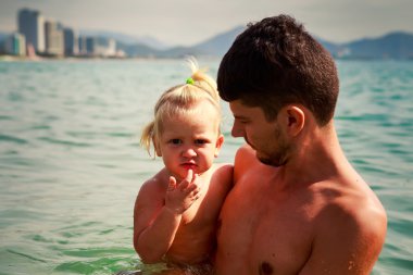 european young father holds smiling little daughter in shallow s