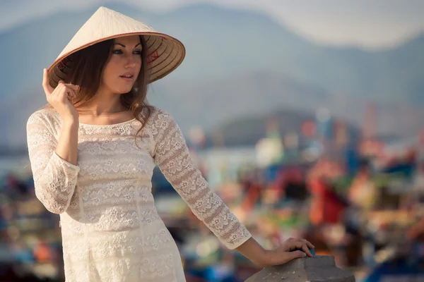 Blonde girl in Vietnamese dress leans on embankment — Stock fotografie