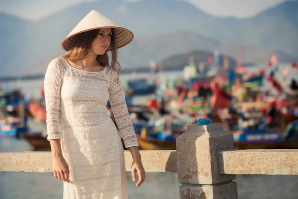 Blonde girl in Vietnamese dress leans on embankment — Stock fotografie