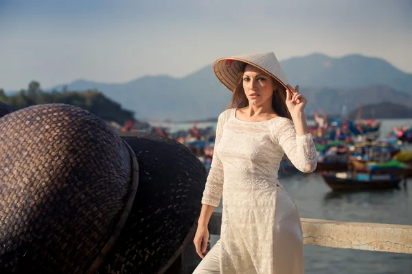 Blondes Mädchen im vietnamesischen Kleid berührt Hut durch Barriere — Stockfoto