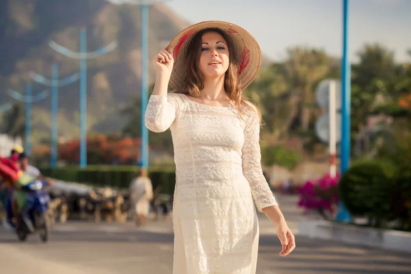 Blonde girl in Vietnamese dress walks against goats flock — Stock Photo, Image