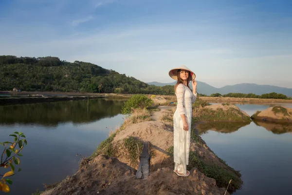 Blonde girl in Vietnamese dress stands among country lakes — ストック写真