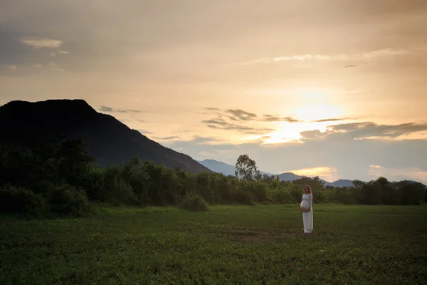 Blonde girl in Vietnamese dress backside view on field — Stockfoto