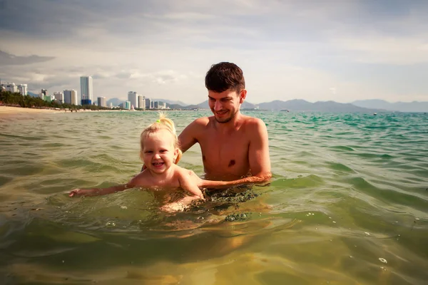 Father teaches little daughter to swim in shallow sea water — Stock Photo, Image
