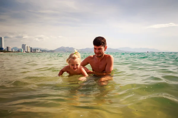 Father teaches little daughter to swim in shallow sea water — Stock Photo, Image