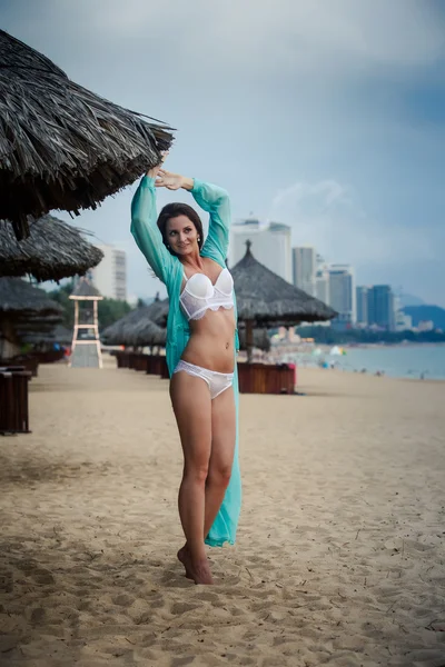 Slim girl in underwear thrown open transparent gown on sand — Stock Photo, Image