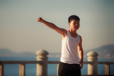 vietnamese boy does exercises on embankment at dawn