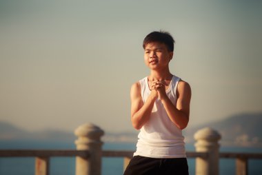 vietnamese boy bends downward on embankment at dawn