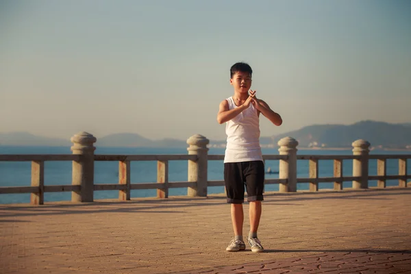 Vietnamese boy does yoga on embankment at dawn — Stock fotografie