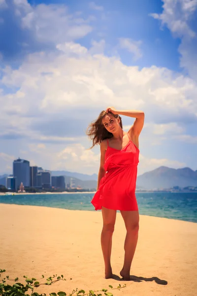 Rubia chica en rojo stands en playa smooths sacudido por viento pelo —  Fotos de Stock