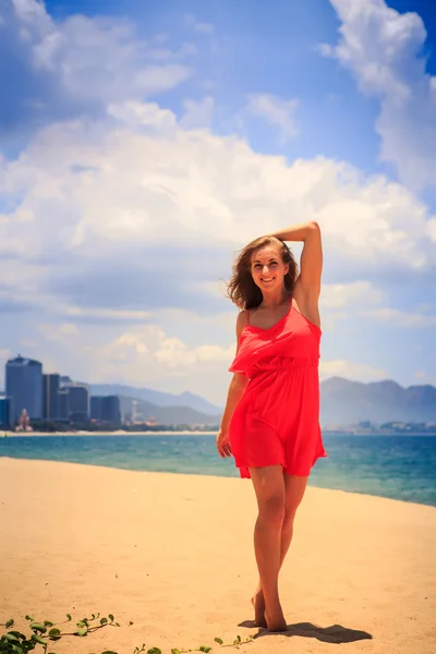Rubia chica en rojo stands en playa smooths sacudido por viento pelo — Foto de Stock