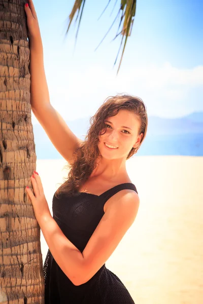 Slim girl in black frock touches palm and smiles — Stock Photo, Image