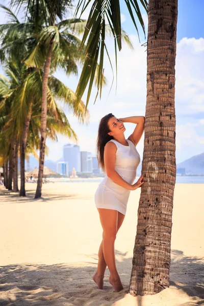 Flicka med stor byst i vitt lutar på palm mot raden av palmer — Stockfoto