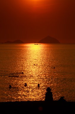 yukarıda deniz günbatımı üzerinde insan siluetleri