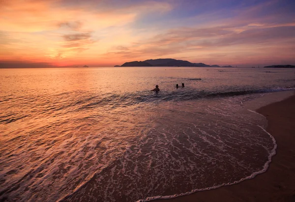 Människor silhuetter över solnedgången över havet — Stockfoto