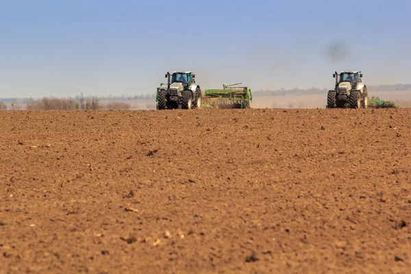 Работающие тракторы в поле — стоковое фото
