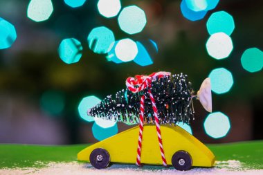 Sarı araba, arkasında Noel ağacı ve ışıkları var.