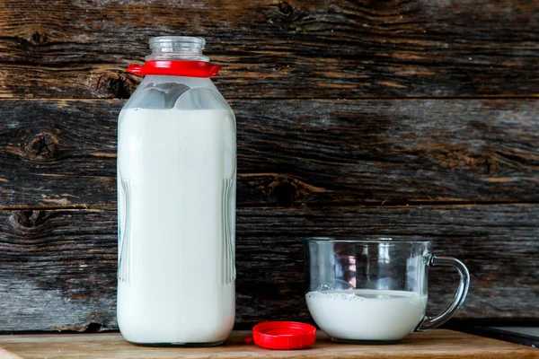 Bottle with organic milk  in kitchen with rustic looking wooden background