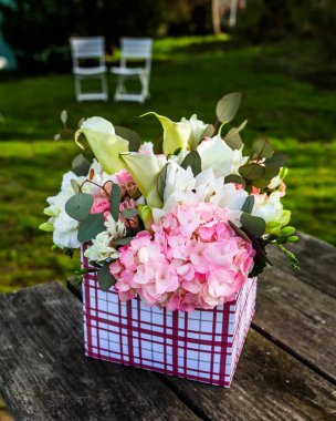 Dışarıdaki ahşap masadaki hediye kutusunda çiçekler.