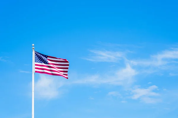 Amaerican flag on pole with blue sky and whiteclouds