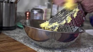 Hand shredding potato into a bowl, preparing for a potato pancake. This activity showcases traditional cooking techniques.