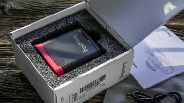 NORWALK, CT, USA- 10 Ekim 2025: SmallRig el feneri açık paketin içinde tahtadan bir yüzeye yerleştirilmiş koruyucu çanta ve kullanma kılavuzu olan şarj kablosunun yanında.