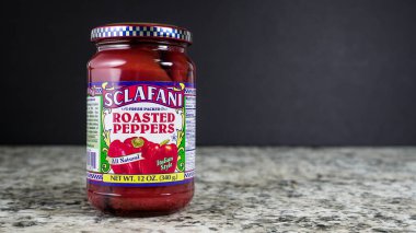 NORWALK, CT, ABD - 30 Ekim 2025: Bir kavanoz kavrulmuş biber mutfak tezgahında duruyor. Canlı kırmızı biberler cam bir kavanoza doldurulur. Dekoratif bir etiketle, tazeliklerini sergilerler..