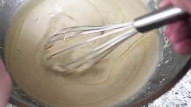 Mixing ready-to-use batter in a bowl with two fresh eggs added for a rich flavor. The kitchen is well-lit, creating a perfect baking atmosphere.