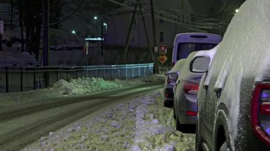 NORWALK, CT, ABD - 09 Şubat 2025: Karla kaplı araçlar kış gecesinde sakin bir caddeye park edilmiş ve sokak lambaları buzlu çevreyi aydınlatıyordu