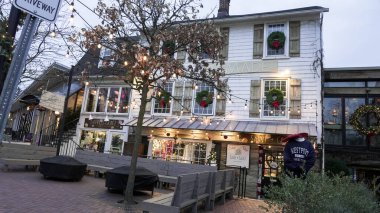 WESTPORT, CT, ABD - 13 Aralık 2025: Nomade mağazasının önünde tatil ışıkları olan akşam caddesi.