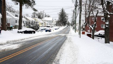 NORWALK, CT, USA- 27 Aralık 2025: kar yolu kaplıyor bir kış fırtınası geçerken. Evler her iki taraftan da görülebiliyor, arabalar cadde boyunca park halinde. Elektrik hatları tepemizde akıyor..
