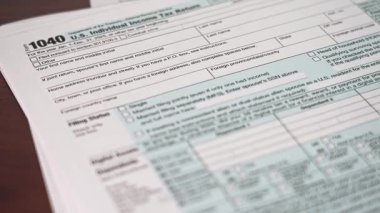 Bir vergi mükellefi 1040 Bireysel Vergi İade formunu masada tamamlar. Formda 2025 vergi yılı için kişisel bilgi ve gelir bölümleri yer almaktadır.