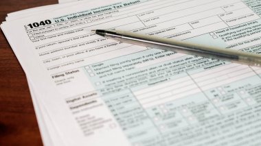 ABD bireysel gelir vergisi iade formu yanında bir kalemle ahşap bir masaya yerleştirilir. Bu sahne vergi sezonunda, vergi beyannamesi hazırlıklarını gösteriyor..