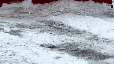 Kar fırtınası sırasında sokaktan kar ve buzu iten kırmızı bir sabanla ağır makineler.